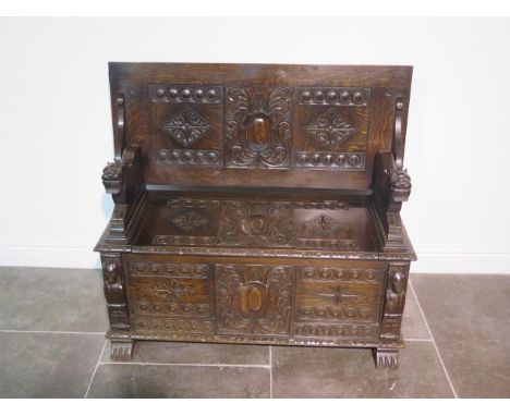 A very good carved oak monks bench, with hinged  seat and panelled storage below, heavily carved panels and back rest, crouch