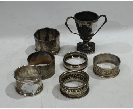 A silver napkin ring, engine turned, Birmingham 1919; four silver napkin rings, one EPNS; a miniature silver trophy, 6cm, Bir