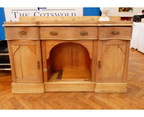 A Victorian pine sideboard with serpentine front, three frieze drawers, open shelf below, flanked by pair of panelled cupboar