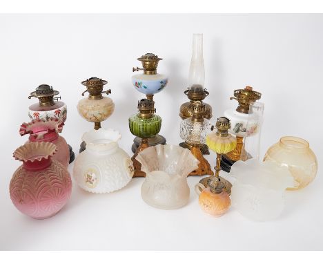 A collection of Victorian and later oil lamps coloured and other glass shades, ornate brass candelabra, chamber stick, pewter