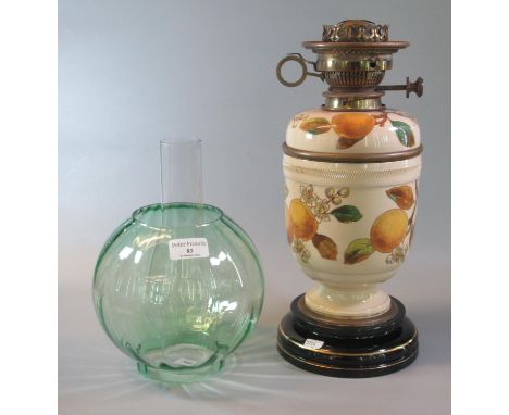 Early 20th Century double oil burner lamp having green glass globular shade, above a ceramic reservoir decorated with fruit a