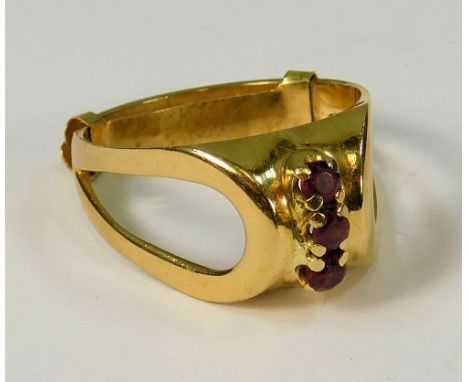 DRESS RING. A 14k dress ring with open shoulders, the front set a row of three rubies.