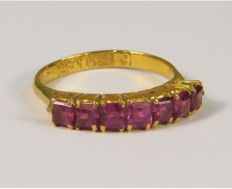 GOLD RING. A high carat gold (tested) half-eternity ring, set with seven square cut rubies, (K).