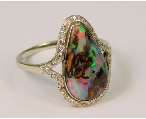 OPAL RING. A late 1930s platinum (unmarked) ring, set a teardrop boulder opal, within a diamond set border. Length of opal 1.