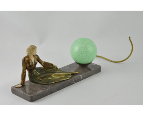 An Art Deco style gilt metal and marble table lamp, cast in the form of a woman reclining wearing a flowing dress with a spec