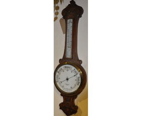 A late Victorian carved oak aneroid wheel barometer, thermometer marked Benetfink & Co., H. 92cm (lacks glass)