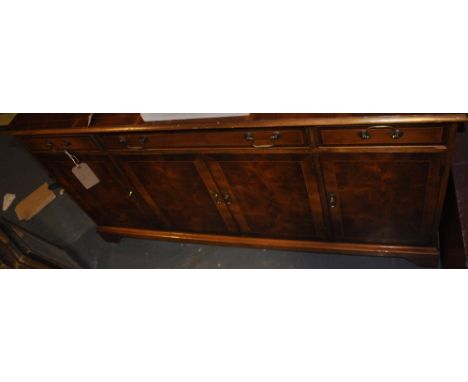 A George III style yew veneer sideboard, the rectangular crossbanded top above an arrangement of four frieze drawers and cupb