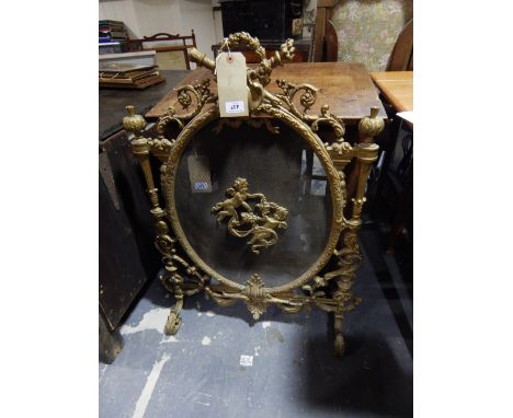 An early 20th century rococo style gilt metal fire screen, the oval mesh panel applied with twin angel plaque within a ribbon