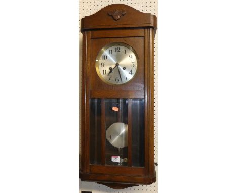 A 1930s oak droptrunk wall clock, with pendulum 