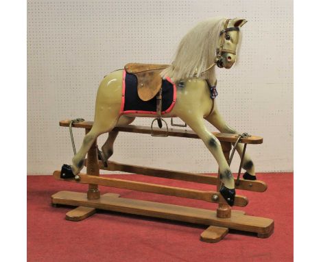 A contemporary dapple-grey child's rocking horse, having a tan leather studded saddle, raised on stained pine base, length 94