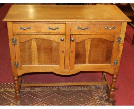 A 1920s light oak dresser base, having twin frieze drawers over twin panelled cupboard doors, w.106.5cm 