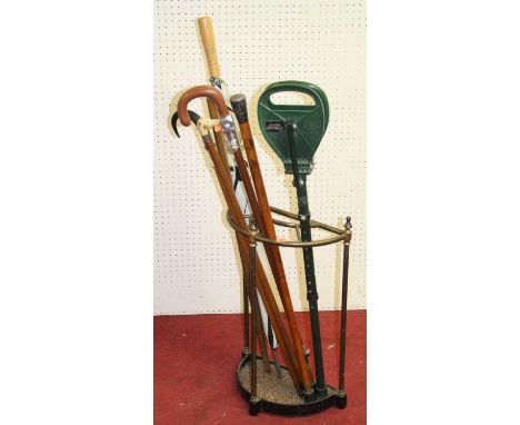 A Victorian cast iron and tubular brass demi-lune four-division stick stand, with sundry walking sticks and umbrellas