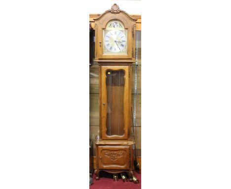 A contemporary provincial French oak Tempus Fugit longcase clock, having an arched brass and silvered dial, three-train movem