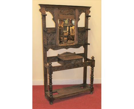 A circa 1900 heavily relief carved oak mirrorback hallstand, with turned hooks, single drawer central compartment, and furthe