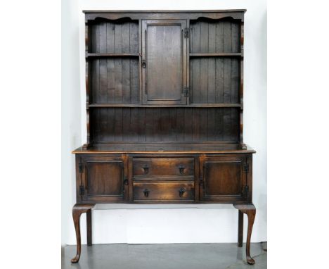 A DARK STAINED OAK DRESSER, THE BOARDED RACK WITH CENTRAL SPICE CUPBOARD, ON CABRIOLE LEGS, 136CM L, EARLY 20TH C