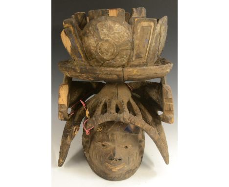 Tribal Art - a Yoruba Gelede helmet mask, lofty cresting, stylised features, carved with geometric motifs and picked out in b