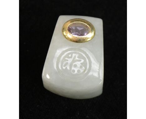 An Indian gold coloured metal and amethyst mounted jade pendant or amulet, carved with a roundel, 2.5cm long