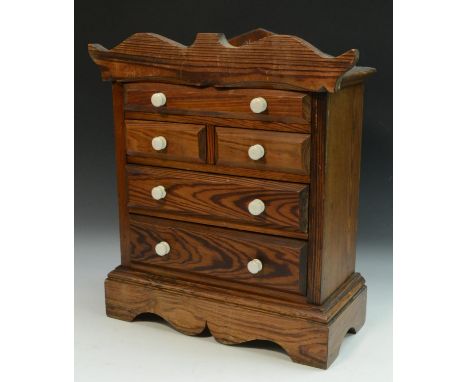 A Victorian pitch pine miniature chest of drawers, shaped cresting and lift-off cover above one long, two short and two furth