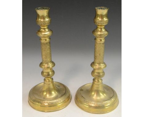 A pair of French Empire gilt brass table candlesticks, urnular sconces, engine turned with flowerhead diapers, dished circula