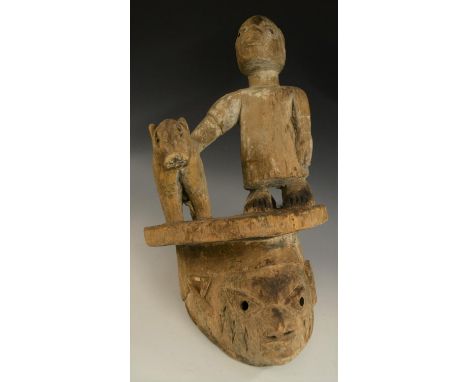 Tribal Art - a Yoruba Gelede helmet mask, crested by a figure and an animal, 55cm high, Nigeria