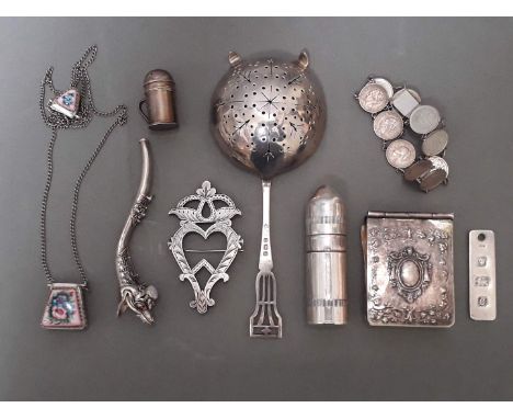 A collection of silver and white metal items including small notes book, tea strainer, ingot pendant, coins bracelet, a brooc