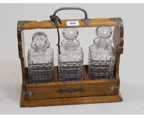 Early 20th Century oak mounted three bottle tantalus with key (one decanter stopper matched) 