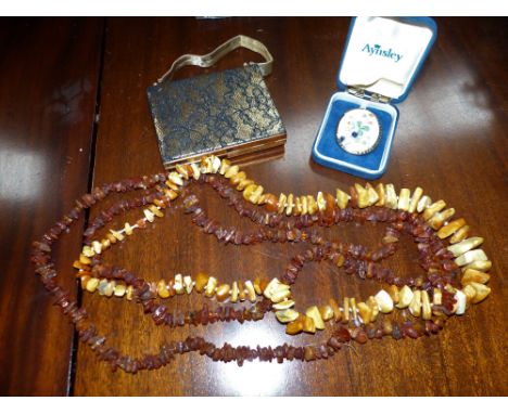 2 necklaces with amber coloured beads; a porcelain brooch; a ladies evening  bag with compact