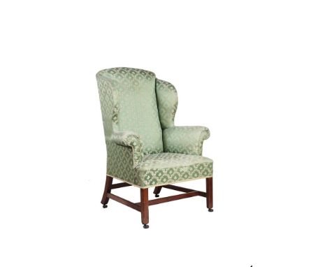 A George III mahogany and upholstered wing armchair, circa 1770, the rounded topped rectangular back above outscrolled arms a