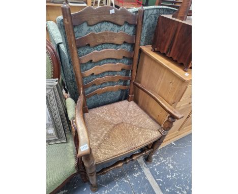 A RUSH SEAT LADDER BACK ARMCHAIR