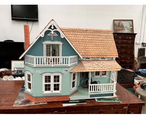 A DOLLS HOUSE WITH A WOODEN SHINGLE ROOF AND ELECTRIC LIGHT