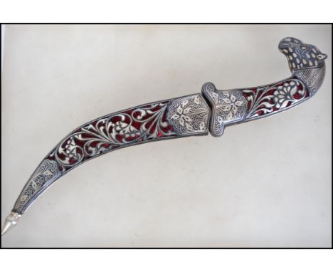 A Silver white metal Persian style dagger with mythical creature to handle and pierced floral pattern to sheath. Measures 31c