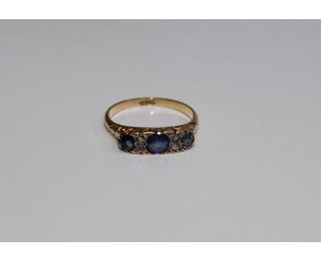 A late Victorian/ Edwardian three stone sapphire and diamond ring. The principal stone approximately 4mm diameter, to an 18ct