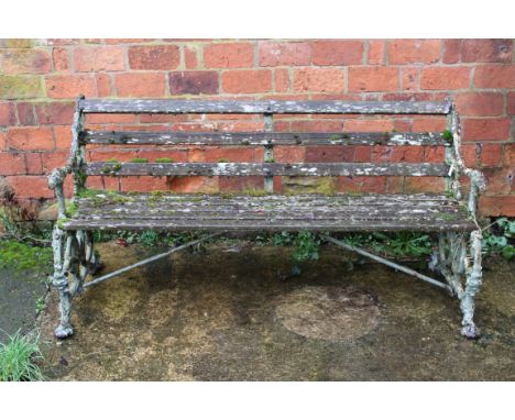 A late 19th century painted cast iron Coalbrookdale framed garden bench, having mask decorated elbows, in serpent and grape p