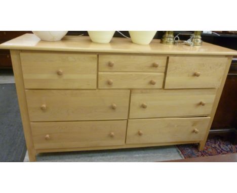 A modern Stanley, light coloured, beech finished chest, having an arrangement of eight long and short drawers, raised on exte