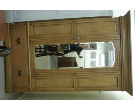 An early 20thC light oak and figured birch wardrobe, having a moulded cornice, over a single mirrored door, enclosing hooks a