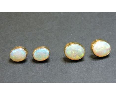 A pair of single stone opal earrings, tested as approximately 18ct gold, and a pair of single stone opal earrings tested as a