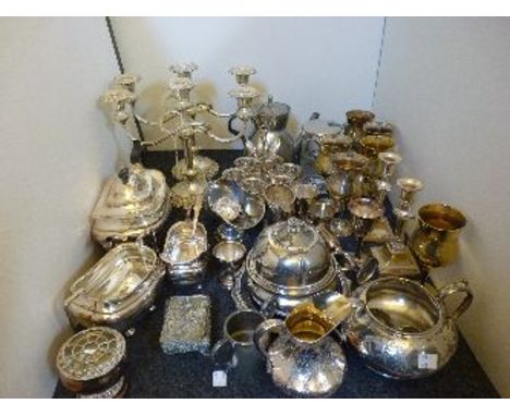 Silver plated items, including a three piece tea service, an egg cruet, and candlesticks