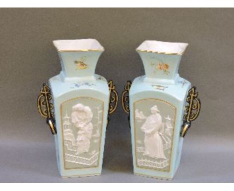 A pair of French porcelain vases, circa 1880, of square form, each with a relief Jasper ware panel depicting Orientals, surro