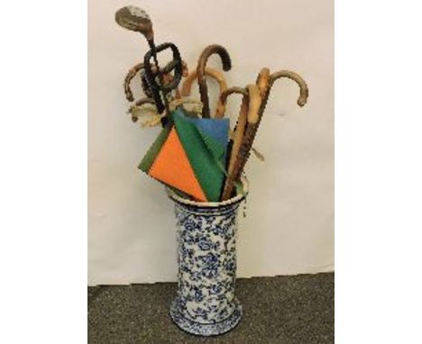 An umbrella stand with umbrellas and sticks, and a box of items including clock, camera, tribal spears, candlesticks, etc