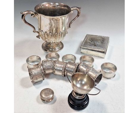 Two silver two handled trophy cups together with a small silver table cigarette box, a small round silver box and 11 napkin r