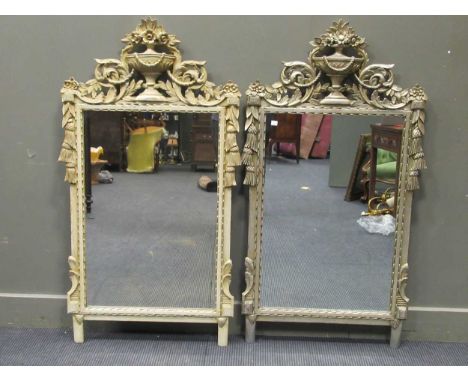 A pair of 20th century silver painted wall mirrors surmounted by classical urns with scrolling foliage 130 x 69cm together wi