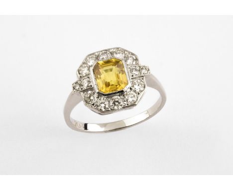 A YELLOW SAPPHIRE AND DIAMOND CLUSTER RING the cut-cornered rectangular-shaped yellow sapphire is set within a surround of ci