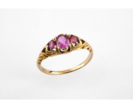 A RUBY THREE STONE RING set with three graduated oval-shaped rubies in yellow gold. Size O