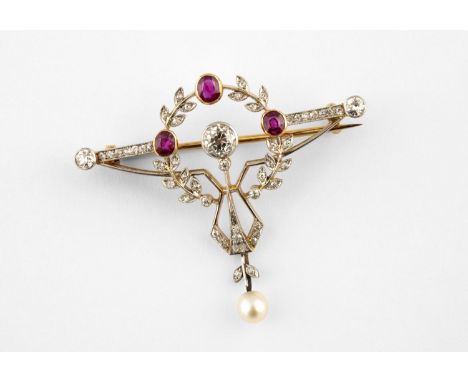 AN EDWARDIAN RUBY AND DIAMOND BROOCH the gold openwork foliate mount centred with a collet set circular-cut diamond, with thr