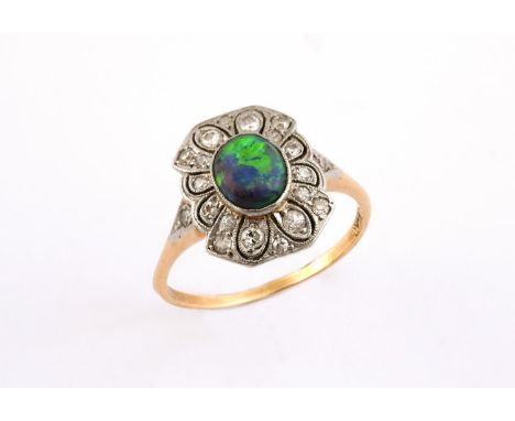 A BLACK OPAL AND DIAMOND CLUSTER RING the oval-shaped solid black opal is set within a surround of circular-cut diamonds, in 