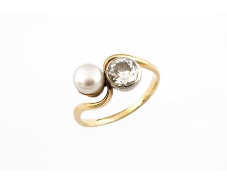 A DIAMOND AND CULTURED PEARL CROSS OVER RING set with a circular collet set diamond and button pearl in yellow gold. Size O