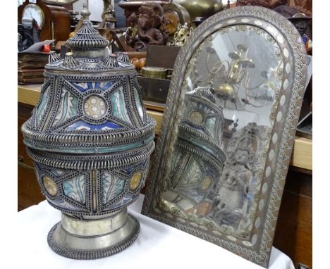 A Middle Eastern painted ceramic pot with ornate wirework decoration, and an inlaid metal framed wall mirror.