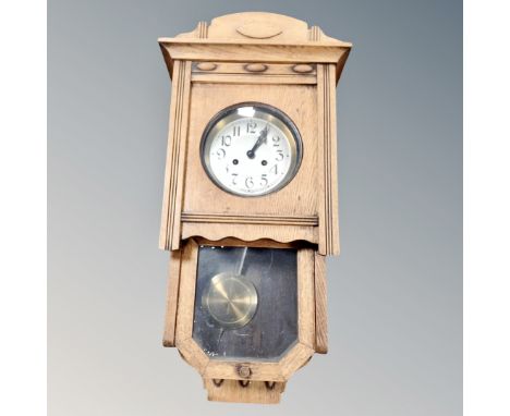 An early 20th century oak eight day wall clock with silvered dial, pendulum and key 