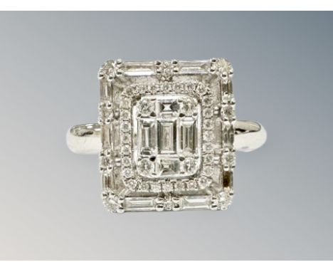An 18ct white gold diamond cluster ring, 4.4g, size K, the tiered cluster set with baguette and round cut diamonds.