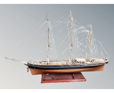 A model of a three masted ship on wooden stand 